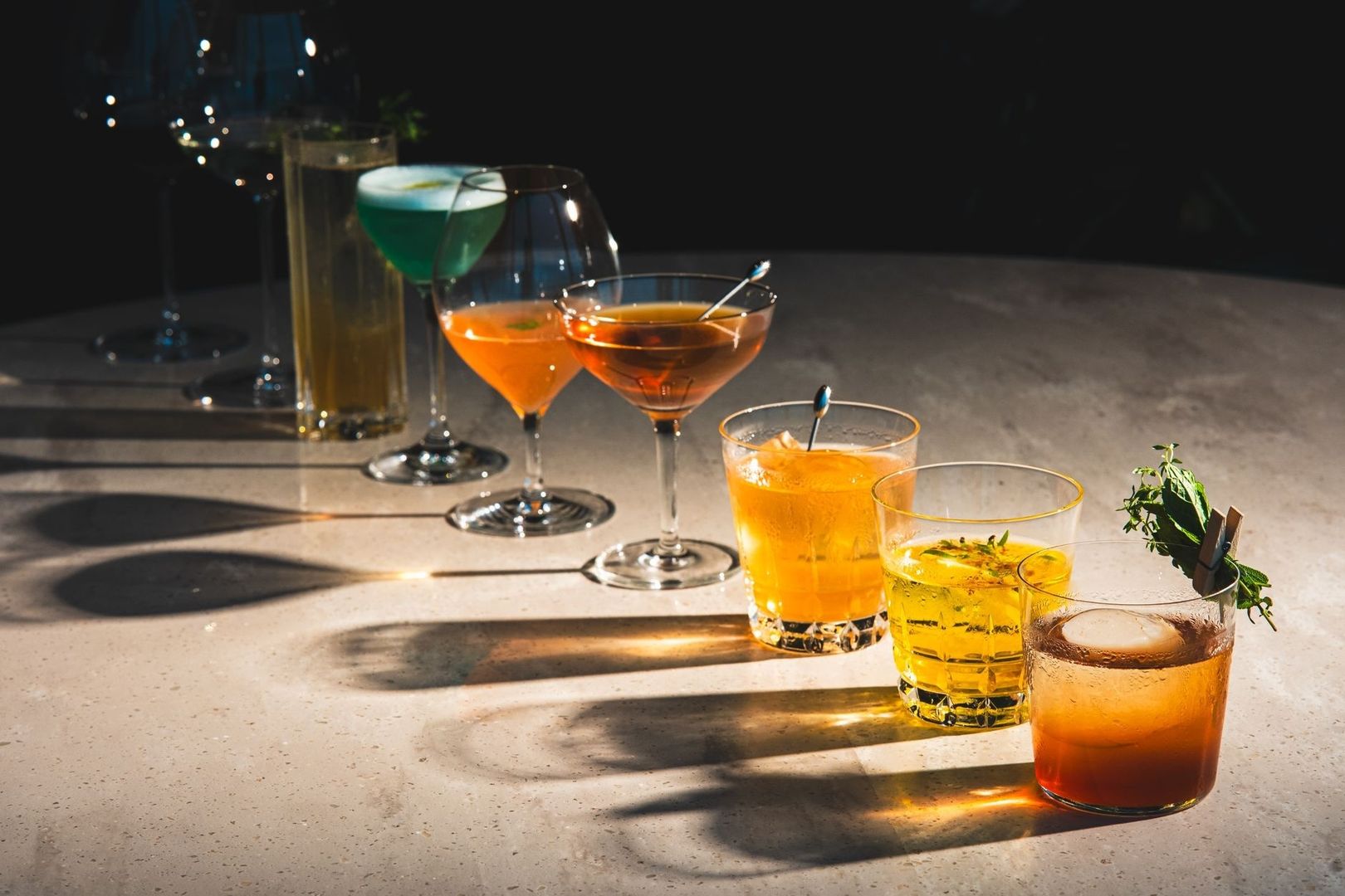 Colorful cocktails and garnished drinks arranged on a sunlit bar